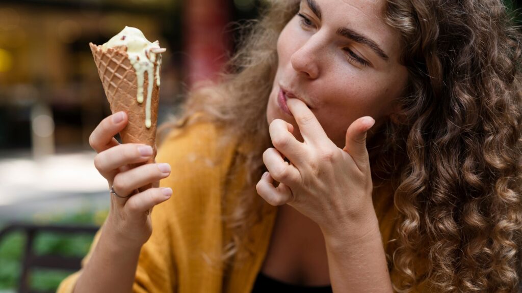 A woman enjoying a thin ice cream cone, savoring the delightful treat on a sunny day